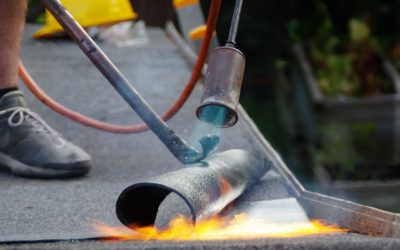 Roof house repair by putting the roofing felt on the surface wit Roof house repair. Putting the roofing felt on the surface with a burner and fire.