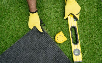 Man’s hands with the artificial grass roll and tools Man's hands with the artificial grass roll and tools
